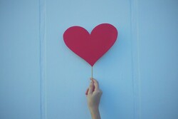 hand holding heart shape on a stick