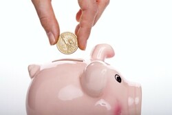hand putting a coin into a piggy bank